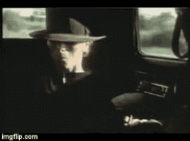 a man in a top hat is sitting in a car .