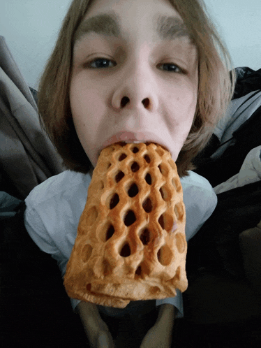 a young boy is eating a waffle cone with his mouth