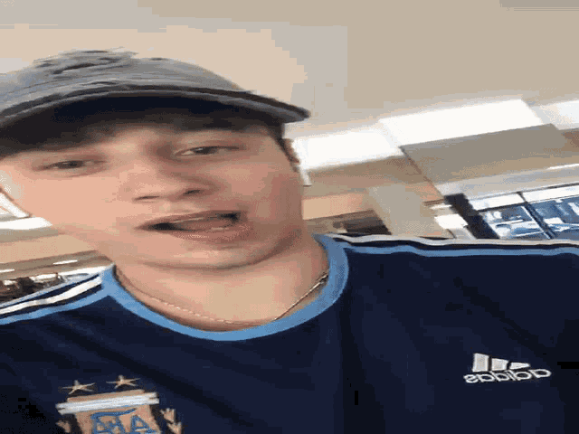 a man wearing a hat and a shirt that says adidas
