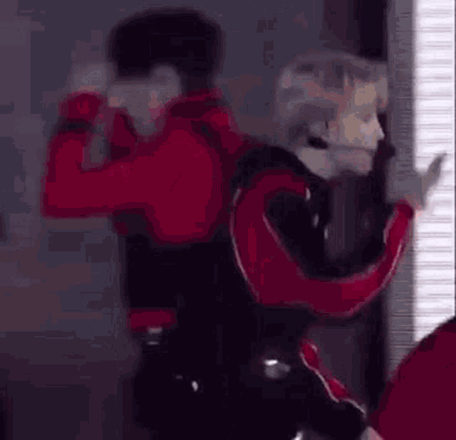 a man in a red and black suit is dancing with a microphone in his mouth .