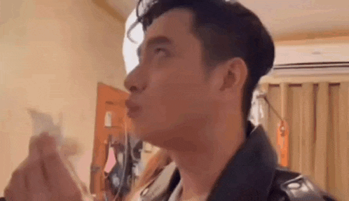 a man is making a funny face while holding a piece of paper in his hand .