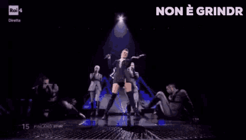 a group of people are dancing on a stage with a woman singing .
