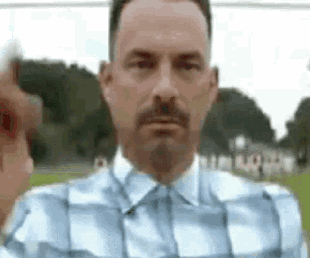 a man with a mustache is giving a thumbs up .
