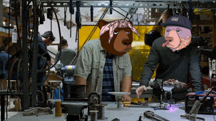 a man with a bandana on his head is standing next to another man wearing a bear head