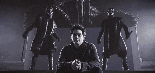 a man is sitting in front of a group of skeletons holding knives .