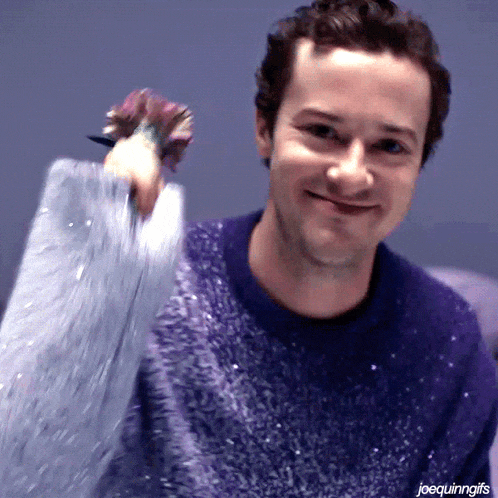 a man in a purple sweater is holding a purple flower