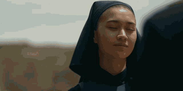 a woman with her eyes closed is wearing a black head scarf