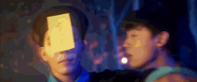 two men are standing next to each other and one has a piece of paper on his face that says ' i love you '