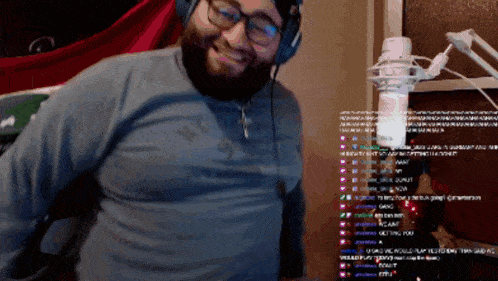 a man wearing headphones is smiling in front of a microphone with a bunch of messages on the screen