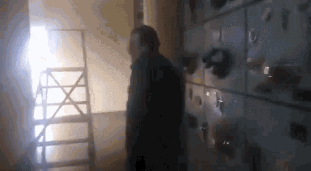 a man is standing in a dark room with a ladder behind him