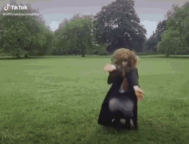 a woman in a harry potter costume is standing in a field .