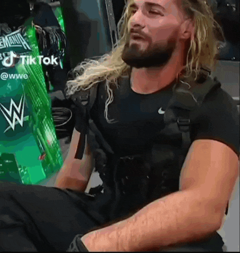 a man with long blonde hair and a beard is wearing a black shirt and black pants .