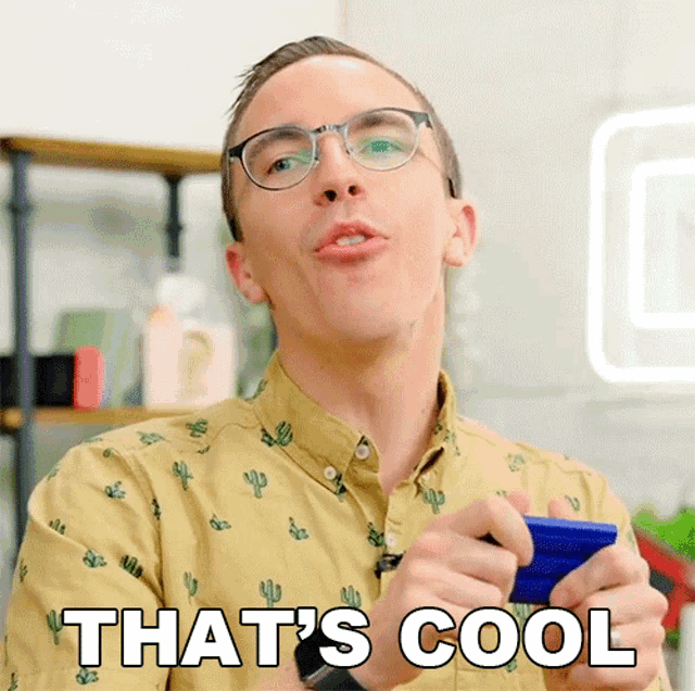 a man wearing glasses and a cactus shirt is holding a blue object and says that 's cool
