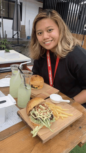a woman sitting at a table with a lanyard around her neck that says ' abercrombie '