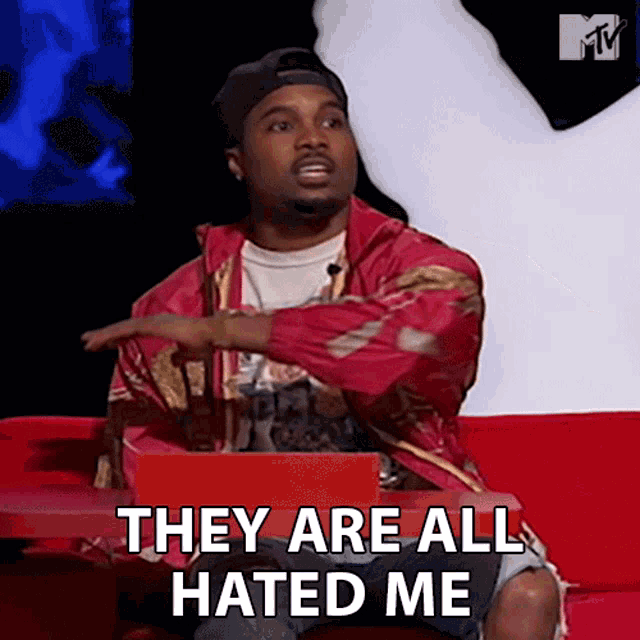 a man is sitting on a red couch with the words they are all hated me