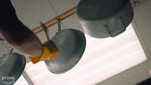 a person cleaning pots and pans hanging from the ceiling with a prime logo in the background