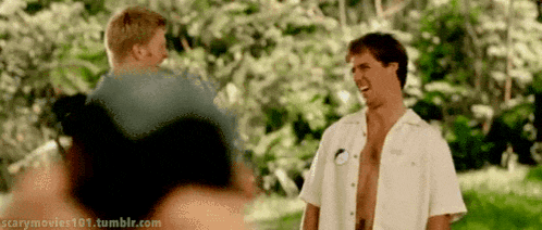 a man without a shirt is laughing with another man in a white shirt .