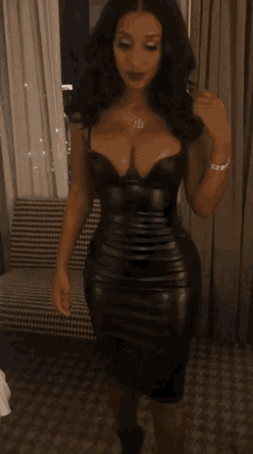 a woman in a black leather dress with a necklace that says ' bb ' on it