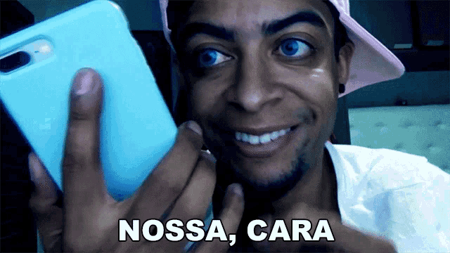 a man in a pink hat is holding a cell phone with the words nossa cara written on it