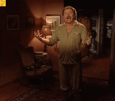 a man in a green shirt stands in a living room with a lamp and chair