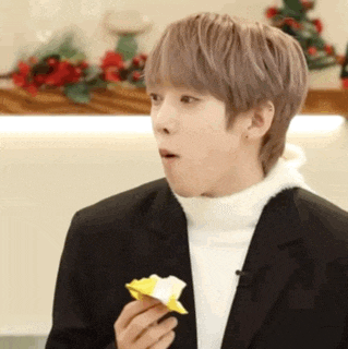 a young man in a suit is eating a piece of origami .