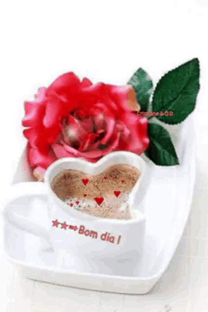 a cup of coffee in the shape of a heart next to a red rose on a white plate .