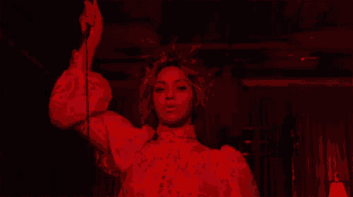 a woman in a white dress is holding a microphone in a dark room