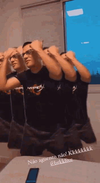 a man wearing a hyperx shirt is standing in front of a mirror .