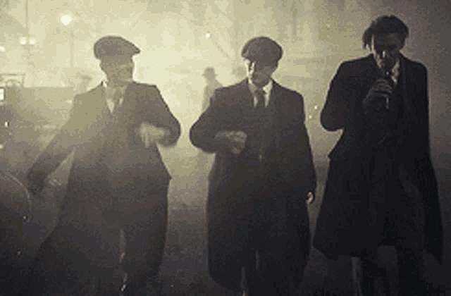 three men in suits and hats are walking in a foggy area