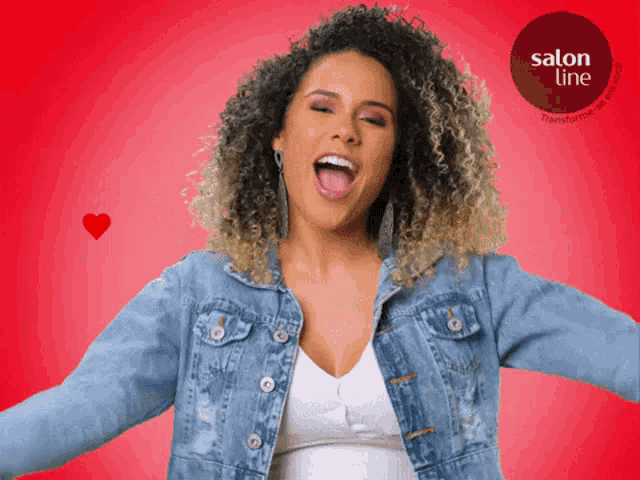 a woman in a denim jacket is standing in front of a red background with a salon line logo