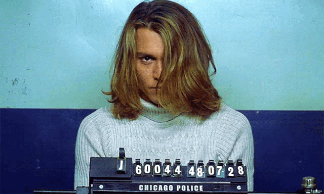 a man with long hair behind a chicago police mugshot