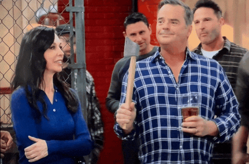 a man in a blue plaid shirt is holding an axe