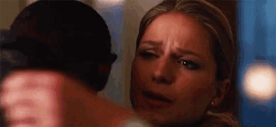a close up of a woman 's face with a man 's arm around her neck .