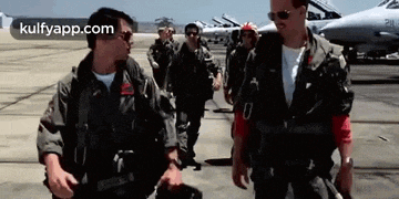 a group of military men are walking on a runway next to a plane .