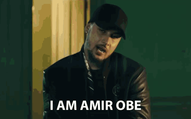 a man wearing a black hat and a black jacket says i am amir obe