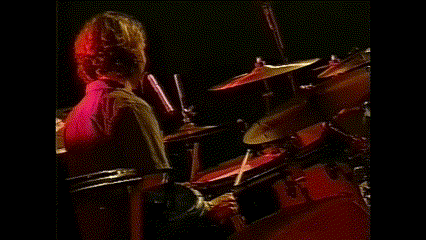 a man in a red shirt is playing drums