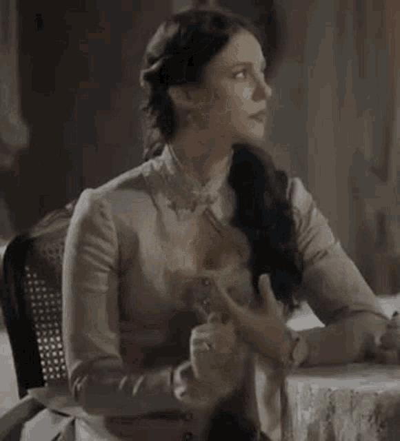 a woman in a white dress is sitting at a table with her eyes closed .