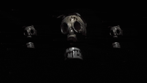three gas masks are sitting next to each other on a black background .