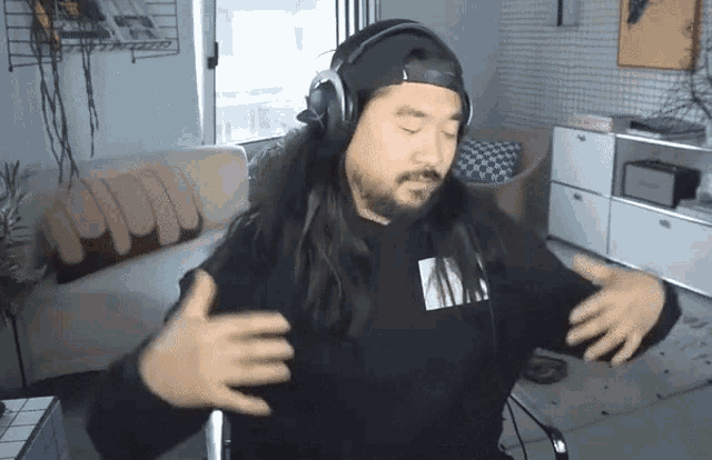 a man with long hair is wearing headphones and a black shirt that says ' nirvana ' on it