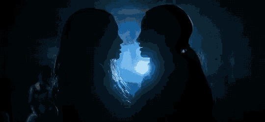 a couple of women standing next to each other in the dark