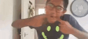 a young boy wearing glasses and a glow in the dark smiley face t-shirt .