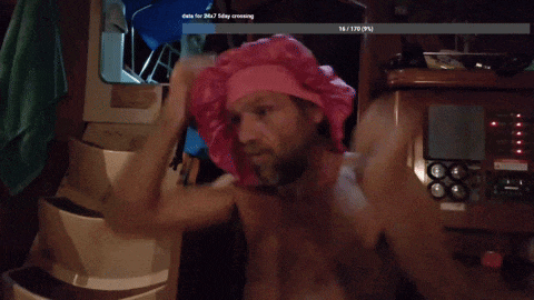 a man wearing a pink hat is sitting in a room with a date for 26.7 day crossing