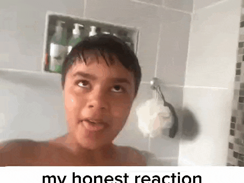 a young boy is taking a selfie in a bathroom with a sponge hanging on the wall .