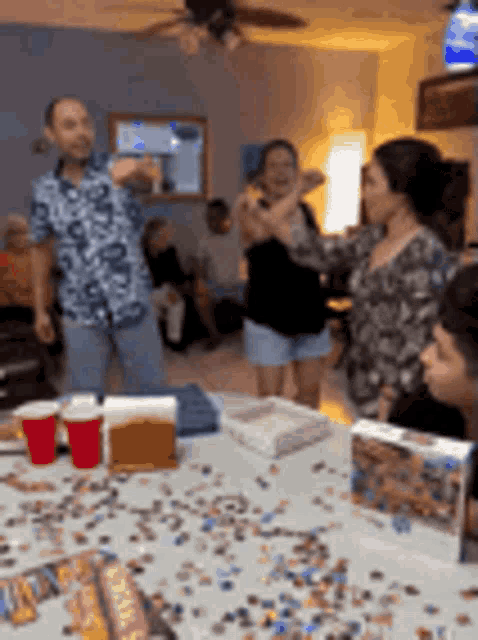 a group of people are gathered around a table with puzzles on it .