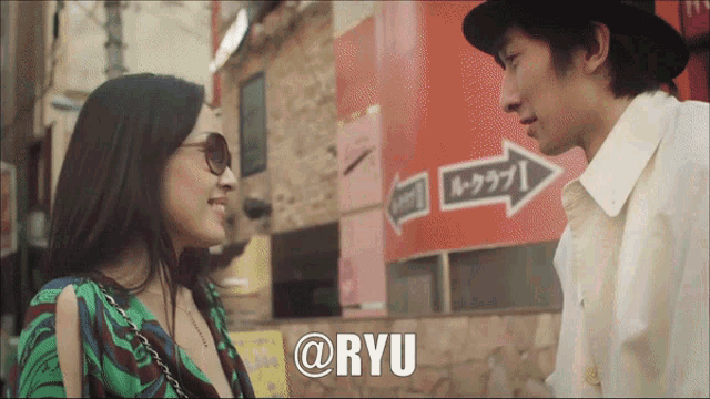 a man and a woman are looking at each other in front of a sign that says ryu
