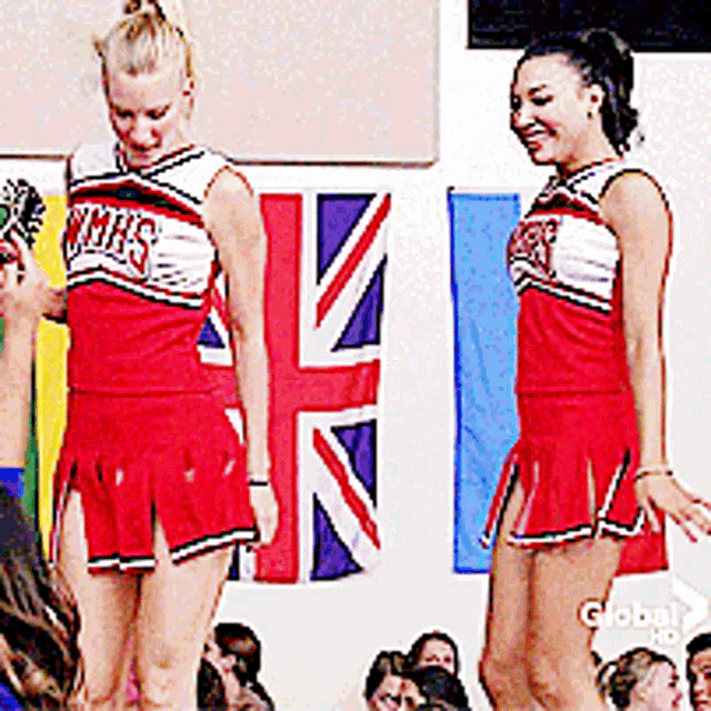 two cheerleaders are standing in front of a crowd wearing uniforms that say wmhs