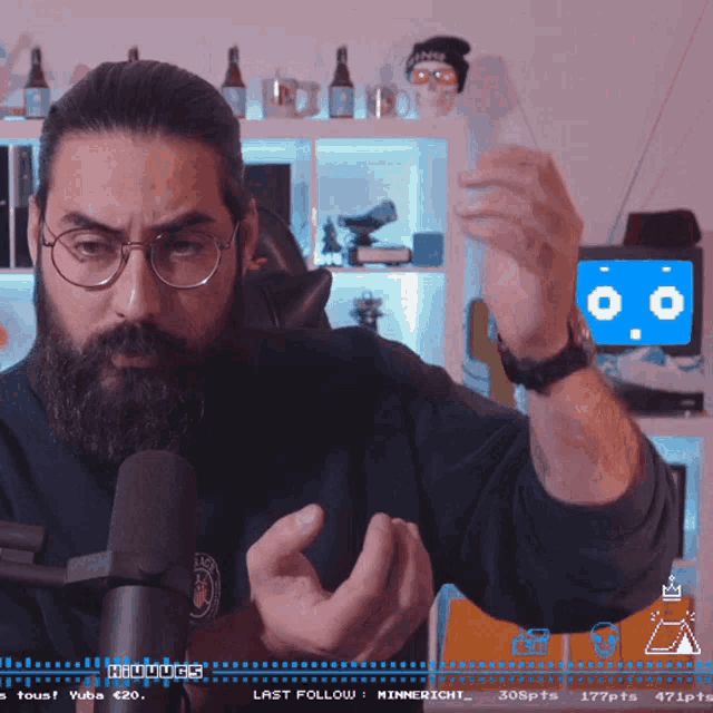 a man with glasses and a beard stands in front of a microphone with a screen that says last follow