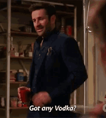 a man in a suit is holding a cup and asking if he has any vodka