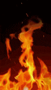 a close up of a fire with sparks coming out of it on a black background
