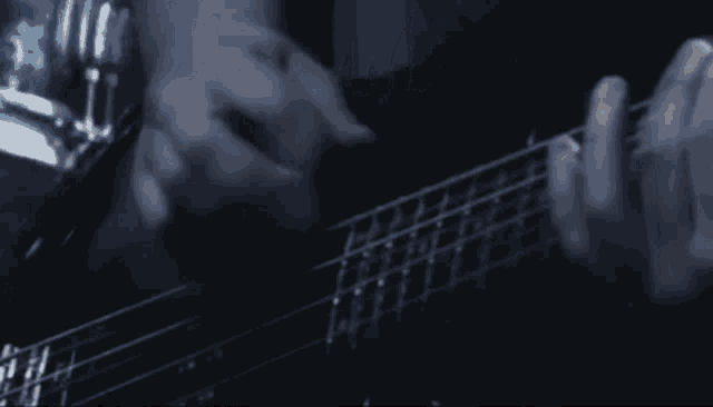 a man is playing a bass guitar in a dark room